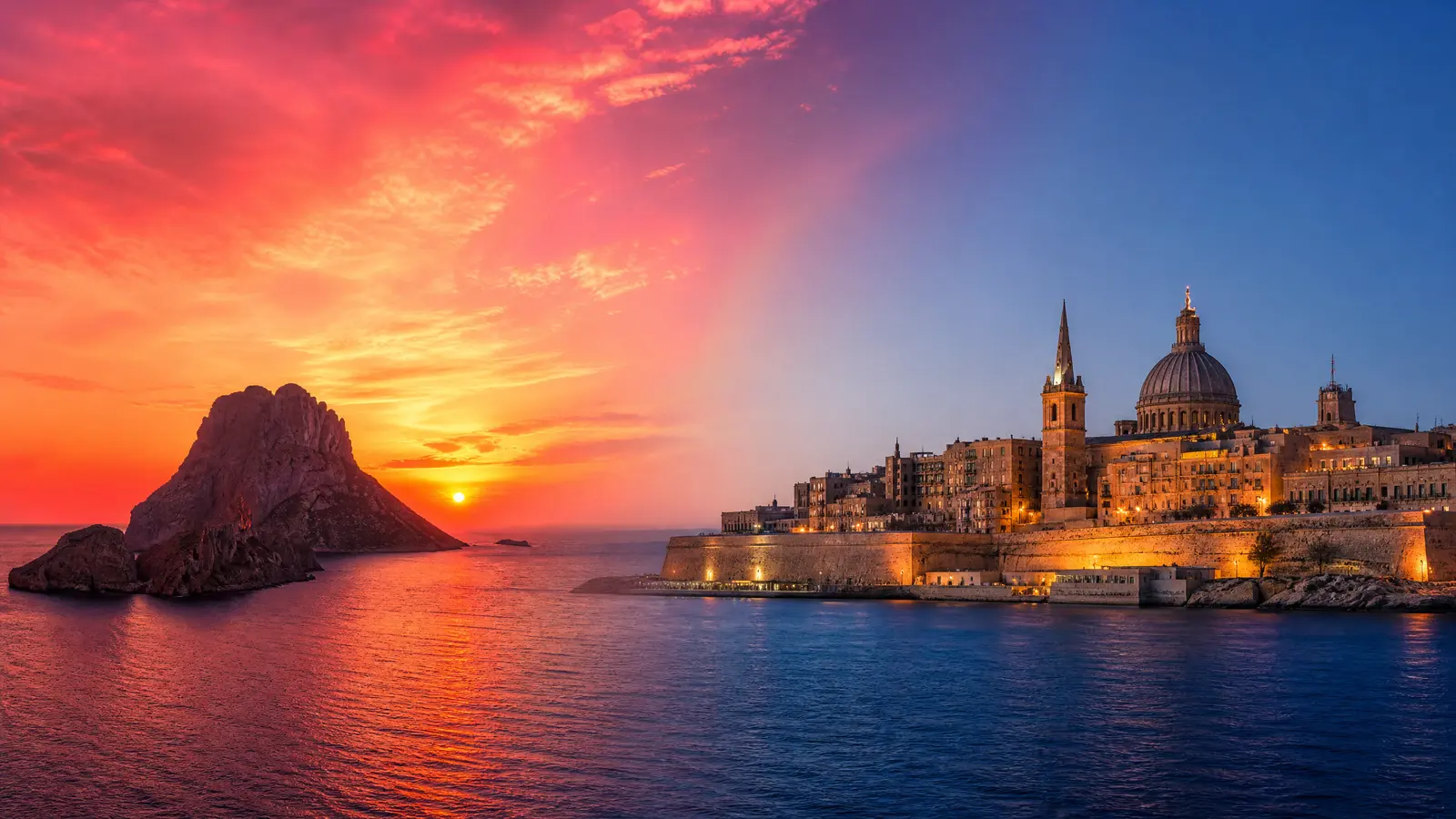 Sunset over Es Vedrà rock off Ibiza blending into the calm illuminated bastions of Valletta at blue hour.